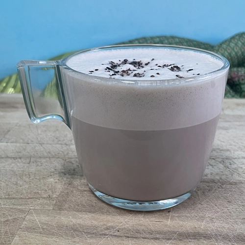 Zelf gemaakte chocolademelk met een dikke schuimlaag en nibs als topping